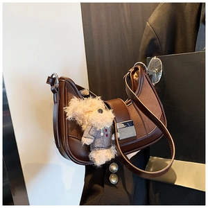 Detail of vintage half-moon bag with patchwork leather, fabric and teddy bear charm