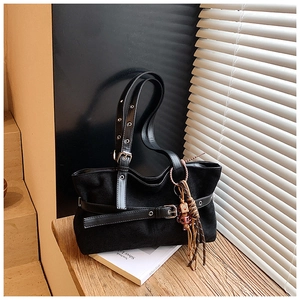Close-up of black vintage suede tote bag with leather buckle and ethnic woven charm