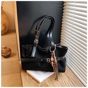 Macro shot of black canvas tote bag with adjustable leather strap and ethnic bear charm