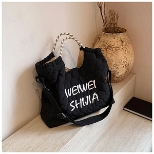 Detail of black quilted tote bag with heart patterns and woven rope handles on marble stairs