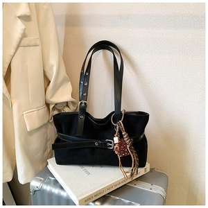 Detail of black suede tote bag with leopard heart charm and silver buckle accent