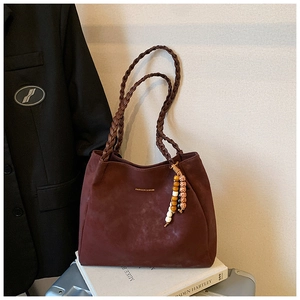 Detail of burgundy suede tote bag featuring braided handles and beaded tassel charms