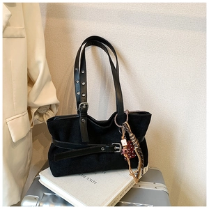 Detail of vintage black suede tote with decorative buckle straps and colorful charms