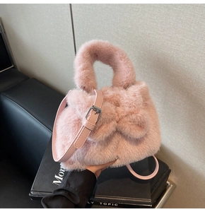 Close-up of pink plush bucket bag featuring a soft faux fur bow and adjustable strap