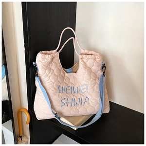 Pink quilted tote bag with blue shoulder strap shown on a wooden cabinet detail view