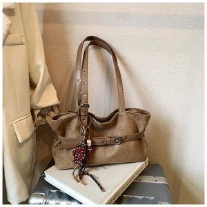 Detail of vintage brown suede tote with adjustable strap and cute bear charm accessory