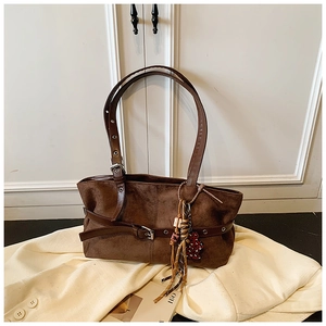 Close-up of vintage brown suede tote with leather tassels and heart charm detail