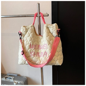 Close-up of quilted cream tote bag featuring pink handles and WEIWEI SHIJIA embroidery