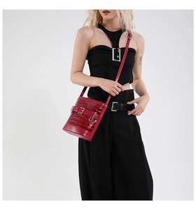 Détail du sac seau bordeaux à motif crocodile, fini brillant et boucles métalliques de style