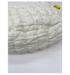Detail einer weiß gesteppten Puffer-Handtasche mit gelbem Fashion-Logo-Etikett