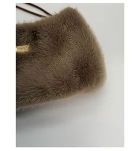 Gros plan sur le tissu en peluche marron doux et la plaque métallique dorée du sac