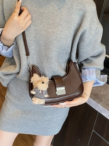 Dark brown half-moon saddle bag with silver buckle and plush bear pendant detail