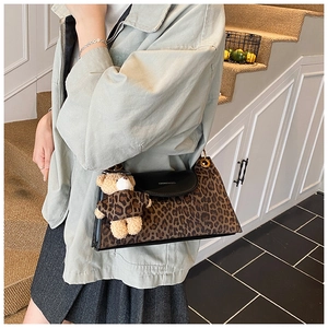 Detail of vintage leopard print shoulder bag with black flap and cute bear charm accessory
