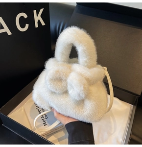 Détail du sac seau en peluche blanche avec poignée en fourrure dans un coffret cadeau chic