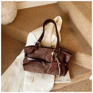 Detail of dark brown suede tote bag with smooth leather strap and cute bear charm