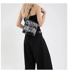 Side view of zebra print bucket bag with black leather straps on a model's shoulder