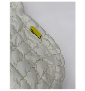 Detail der cremeweißen gesteppten Tasche mit bauschiger Textur und modischem Label