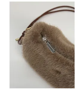 Détail d'un sac bandoulière en peluche marron avec fermeture éclair argentée lisse