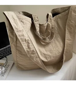 Khaki tote bag detail showing lightweight pleated texture and wide strap with a laptop