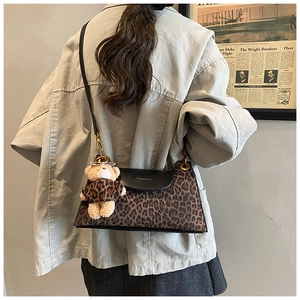 Détail d'un sac à bandoulière léopard avec un pendentif ours et un rabat en cuir