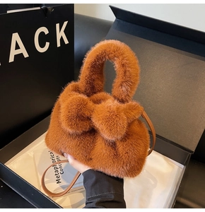 Sac seau en fausse fourrure marron avec anses rondes et bandoulière dans une boîte