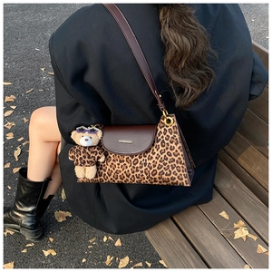 Macro shot of leopard print handbag with brown leather flap and stylish bear charm accessory