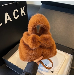 Détail d'un sac seau en peluche marron avec bandoulière dans un coffret cadeau noir