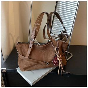 Close-up of brown suede tote bag featuring silver eyelet straps and bear charm