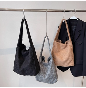 Lambswool tote bags in black, grey and camel hanging on a minimalist display