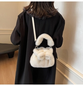 Gros plan du sac à bandoulière en fausse fourrure blanche avec pompons et boucle en cœur