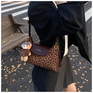 Détail du sac à bandoulière léopard avec rabat en cuir et charm en forme d'ours
