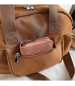 Close-up of brown nylon travel bag with front zip pockets and pink quilted coin purse