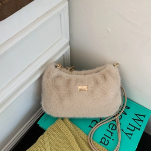 Détail du sac à bandoulière en peluche beige avec plaque logo dorée et fine lanière