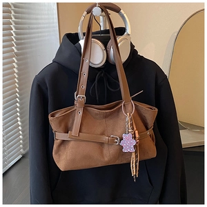 Detailed view of brown suede tote bag with pink leopard bear charm and adjustable straps