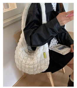 Detail der weißen gesteppten Bubble-Tasche mit Umhängeriemen und gelbem Seitenetikett