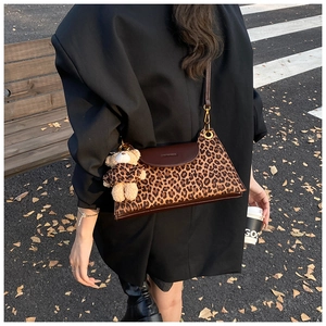 Outdoor shot of a vintage leopard print shoulder bag featuring a cute teddy bear pendant
