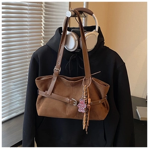 Detail of vintage brown suede tote bag with leather straps and pink bear charm decoration