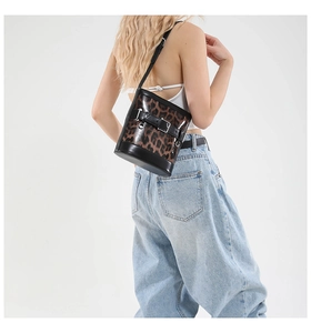 Gros plan du sac seau à imprimé léopard avec bordures en cuir noir et boucle métallique