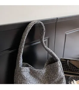 Detail view of the wide shoulder strap on a textured grey fleece tote bag