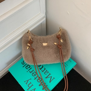 Détail d'un sac à main en peluche marron avec logo en métal doré et lanières en cuir