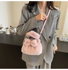 Sac seau rose en peluche avec un grand nœud et bandoulière en cuir porté par un mannequin