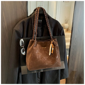 Detail of dark brown suede tote with woven handles and decorative wooden beads