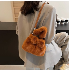 Détail du sac seau en peluche caramel avec bandoulière en cuir sur modèle