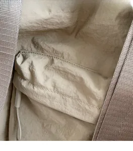 Detail of soft beige wrinkled fabric and fine stitching on a large tote bag