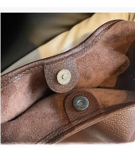 Close-up of magnetic metal clasp on brown leather tote with soft velvet lining