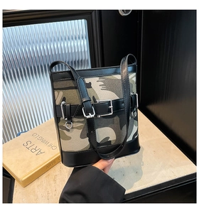 Détail du sac bandoulière en toile camouflage avec bordure en cuir noir et œillets