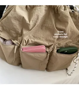 Detailed view of khaki nylon crossbody bag showing multiple front zipper pockets for storage