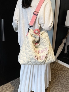 Beige quilted nylon tote bag with pink straps and embroidery shown on a model