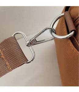 Detailed close-up of a silver metal swivel hook and brown woven shoulder strap on a bag