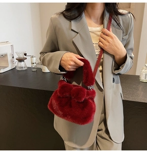 Détail du sac bandoulière en peluche bordeaux avec nœud sur un costume gris